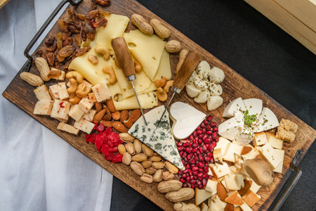 Top view on wooden board on the table with food served various flavor of cheese raisins and dry fruitの写真素材
