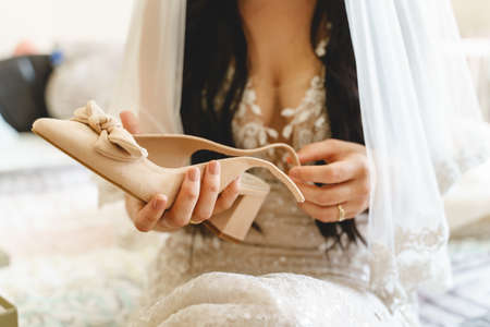 Midsection of unknown woman bride holding a shoe while preparing for weddingの写真素材