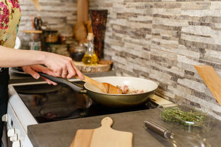 Cooking pan and hands of unknown caucasian woman housewife preparing meal in the kitchen at homeの写真素材