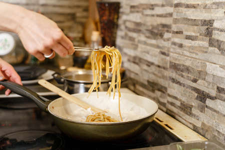 cooking pasta hand of unknown caucasian woman holding food while preparing mealの写真素材