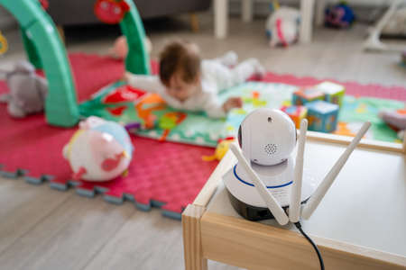 Baby monitor surveillance camera watching 5 months old child playing alone at homeの写真素材