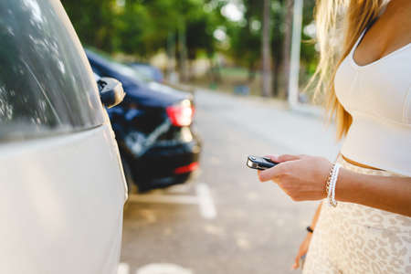 Close up on hand of unknown caucasian woman holding car key while approaching to lock or unlock the vehicleの写真素材