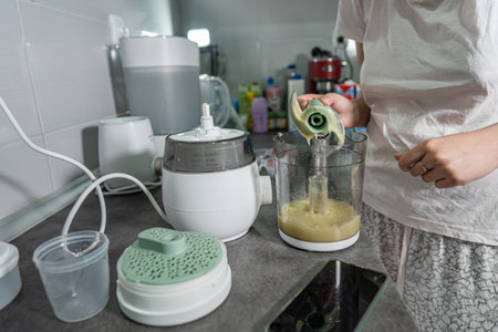 Close up on the electric blender in hand of unknown woman holding it on the kitchen counter...