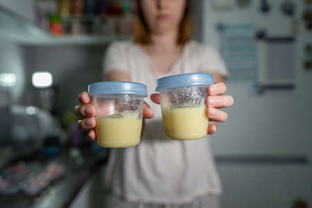 Close up on hands of unknown caucasian woman holding plastic storage cups containers with potato mash meal pureeの写真素材