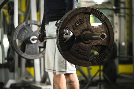 Side view of unknown caucasian man holding barbell weight grip at gym lifting weights in training dead-lift position midsection copy spaceの写真素材