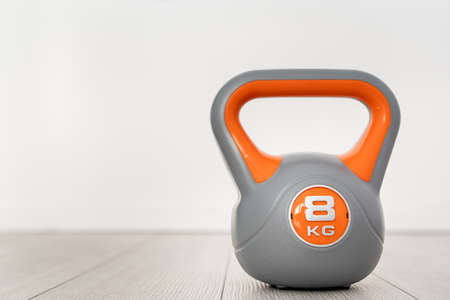 One plastic kettlebell weight 8 kg gray and orange training equipment on the floor copy space