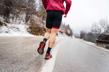 One adult caucasian man running in winter day male athlete runner training on the open road in...