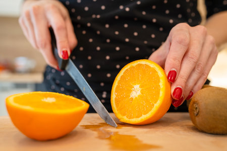 Close up on hand of unknown caucasian woman holding knife cutting oranges copy spaceの写真素材