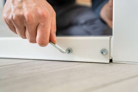 One man unknown caucasian male sitting on the floor at home Putting Together Self Assembly Furniture...