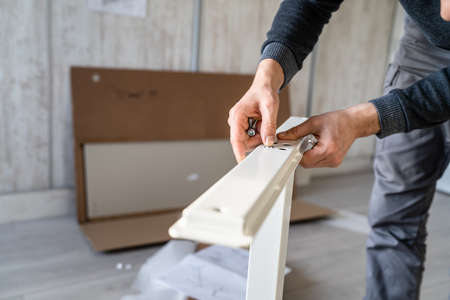 One man unknown caucasian male sitting on the floor at home Putting Together Self Assembly Furniture diy assembly holding parts and instructions real people copy space focus on handsの写真素材