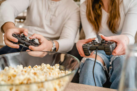 Close up on hands of unknown man and woman holding video game console controller playing video games