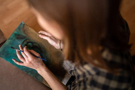 Close up on hands of unknown female artist caucasian woman or girl painting on canvas using brush and colors to make art professional or hobbyの写真素材