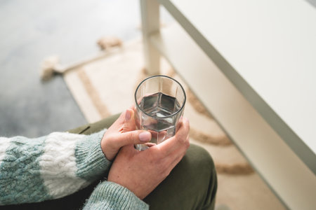 close up on midsection of unknown caucasian woman hold glass of waterの写真素材