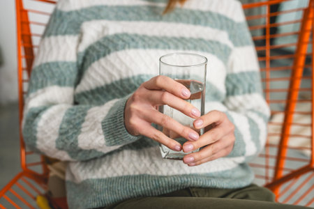 close up on midsection of unknown caucasian woman hold glass of waterの写真素材