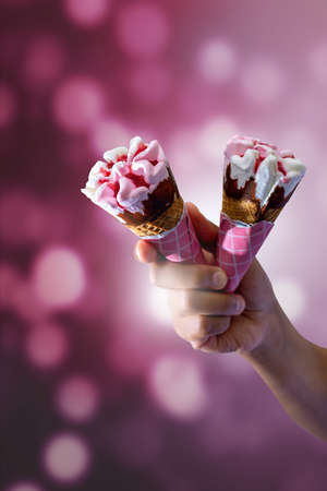 delicious strawberry and cream ice cream, with strawberry sauce inside and on topping, holding ice...
