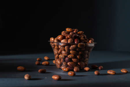 Pinto beans in glass pot, light and shade, black background, photographyの写真素材