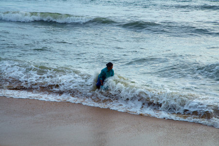 Kerala, India - 22 August 2021: Fisherwomen fighting against strong waves for collecting oyster , Kuzhuppilly Beach Kerala Indiaのeditorial素材