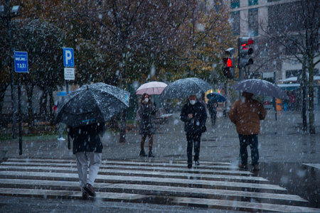Valladolid, Spain - 23 November 2021: Peoples crossing road during snow heavy falling in city, Valladolid Spainのeditorial素材