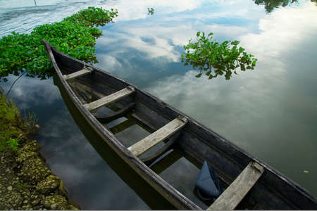 Old wooden fishing boat, Old wooden fishing boat in a lake water with reflections of the sky