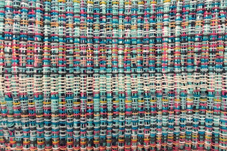 Rough fabric is woven of threads of different colors. Textile background. Needlework and sewing.