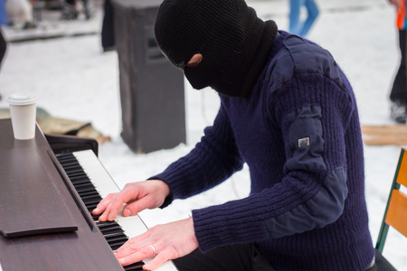 A pianist plays in a black mask on the streetの写真素材