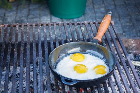 Fried eggs in a frying pan fried on a grill outdoorsの写真素材