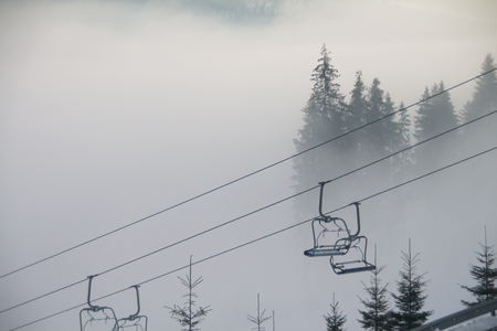Dense fog in the mountains at dawn and empty ski liftsの写真素材