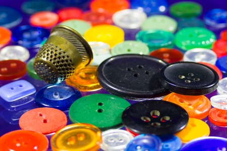 Many round colored buttons of different sizes and a thimbleの写真素材