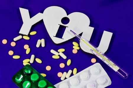 Many different multi coloured tablets and classical thermometer on i love you background
