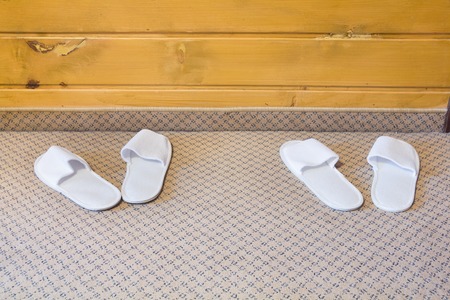 a pair of hotel slippers are white on the carpet in the hotelの写真素材