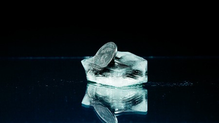 Five cents frozen in melting ice on the black background