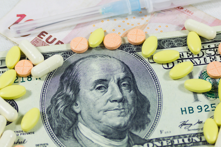 One hundred dollars and tablets of different color and shapeの写真素材