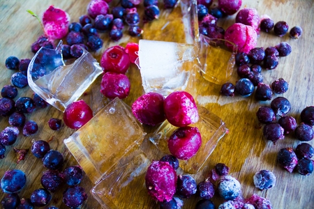 Closeup of frozen cherries and black currant covered by hoarfrost and ice piecesの写真素材