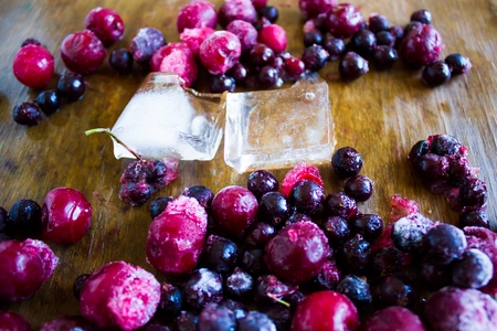 Closeup of frozen cherries and black currant covered by hoarfrost and ice piecesの写真素材
