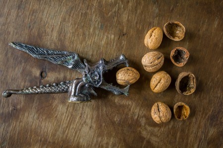 Vintage Original Nutcracker in the form of a dragon chop walnuts next to the peel on a wooden...