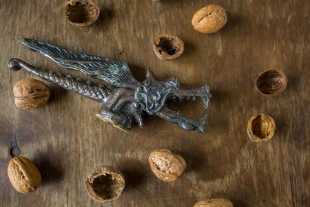 Vintage Original Nutcracker in the form of a dragon chop walnuts next to the peel on a wooden backgroundの写真素材