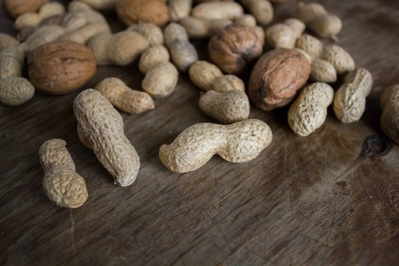 Walnuts and peanuts in a peel on a wooden tableの写真素材