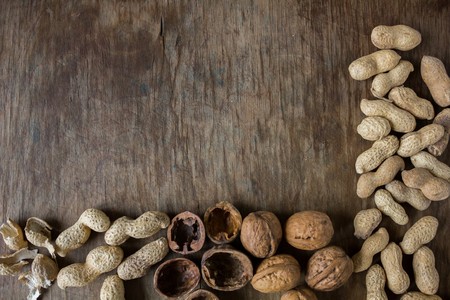Walnuts and peanuts in a peel on a wooden table