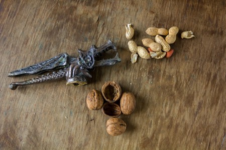 Walnuts and peanuts in a peel and vintage Dracon Nutcracker on a wooden tableの写真素材