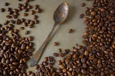Vintage old rusty spoon and black coffee beansの写真素材