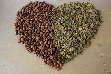 Heart of grains of black coffee and green tea leaves on the original steel backgroundの写真素材