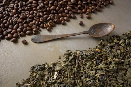 Grains of black coffee green tea leaves vintage rusty spoons on a stylish and fashionable steel backgroundの写真素材