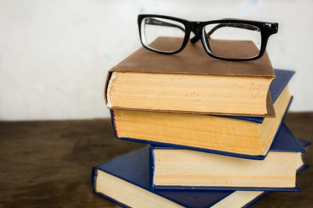 A stack of old big books and glasses on themの写真素材