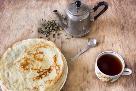 Stack of pancakes vintage teapot cup with floral print green tea leaves and a teaspoonの写真素材