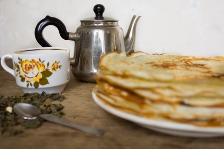 Stack of pancakes vintage teapot cup with floral print green tea leaves and a teaspoonの写真素材