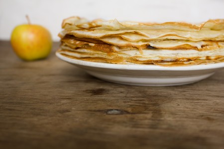 Stack of pancakes and apple on the wooden table and white backfroundの写真素材