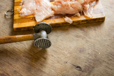 Cooking chicken chops chicken meat hammer beating on the original wooden tableの写真素材