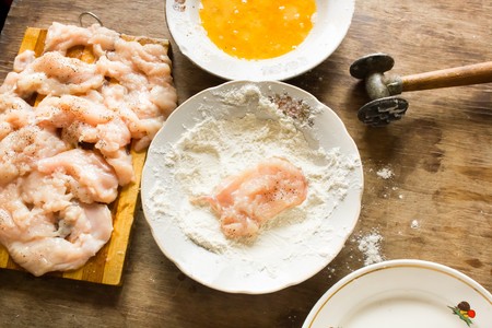 Many thin strips of chicken fillet prepared for cooking chops flour and beaten eggs in the plate