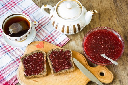 light breakfast or lunch , Raspberry jam slices of black bread Vintage cup of tea and teapotの写真素材