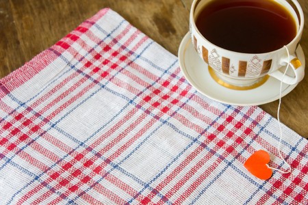 Beautiful vintage gilded cup of black tea and the label in the form of heartの写真素材